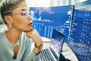 Woman, thinking at computer screen with trading, dashboard and financial information with investmen