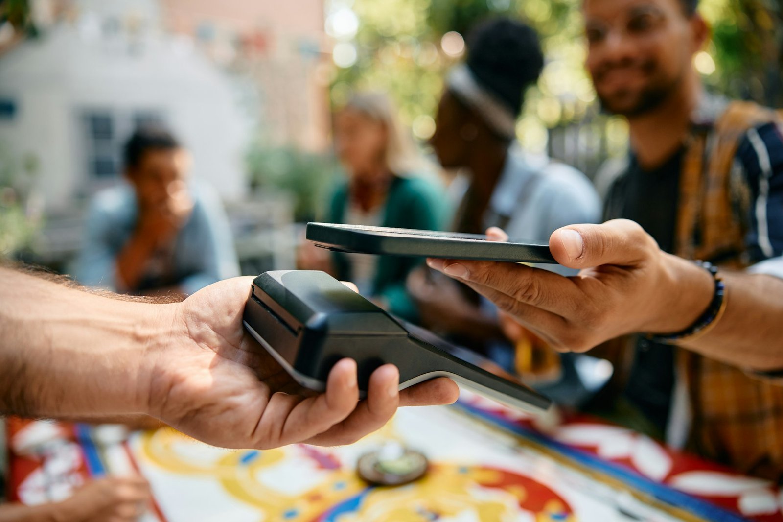 Close up of man using smart phone while paying to a waiter in a cafe.