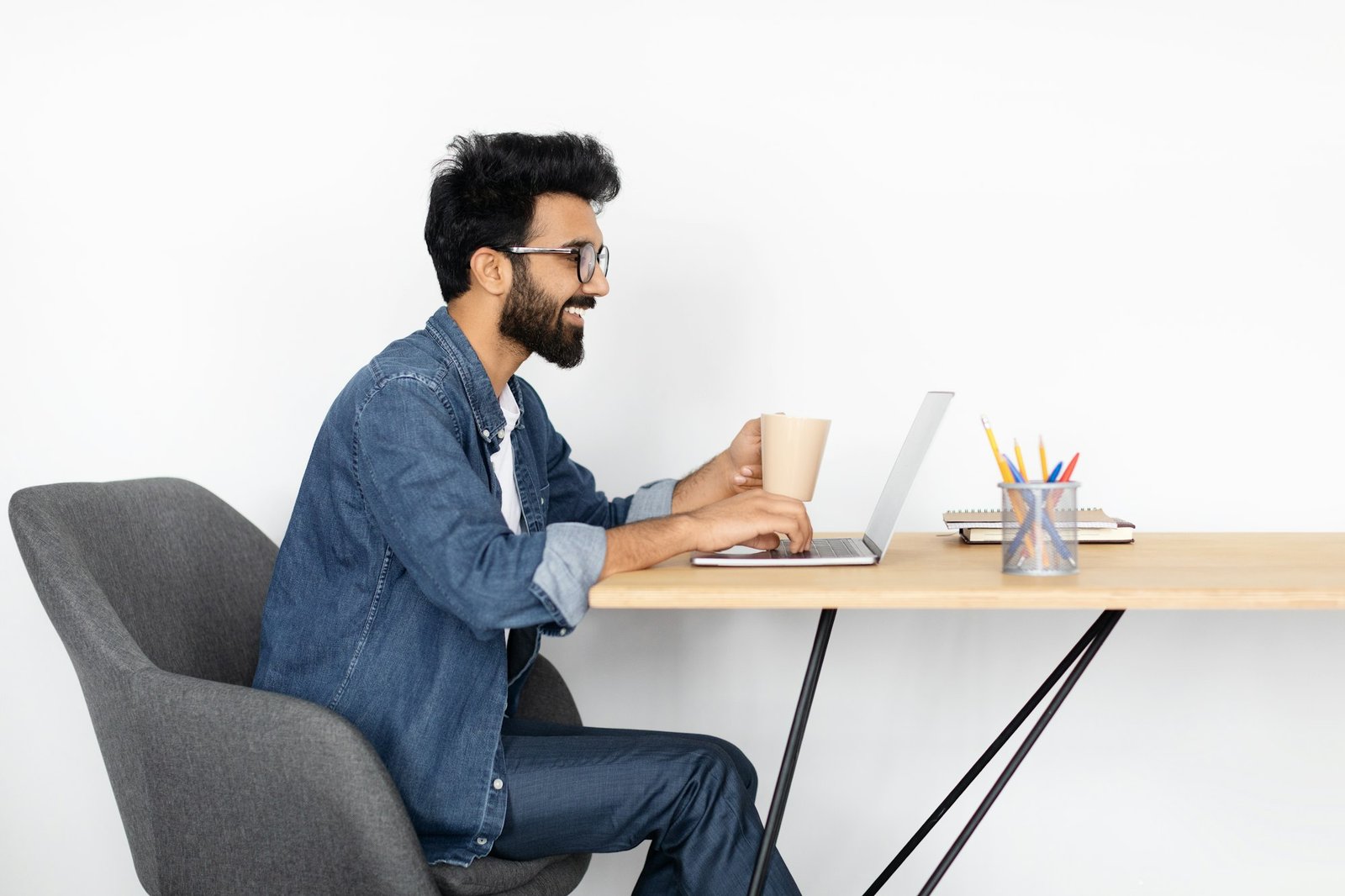 Focused Indian Freelancer Using Laptop at Table